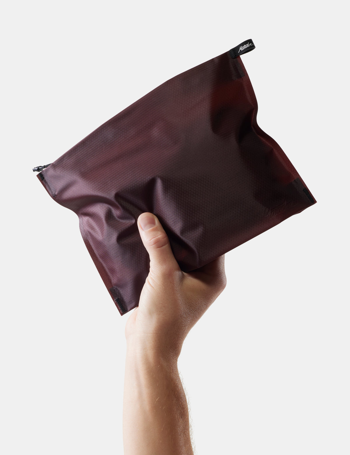 hand holding garnet toiletry case on white background