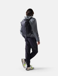 Person wearing a gray raincoat and black pants with a backpack on a white background