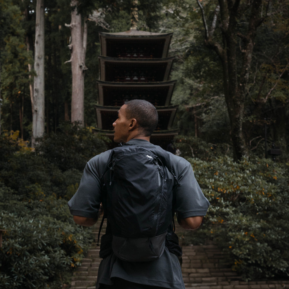 man wearing black backpack in front of shrine