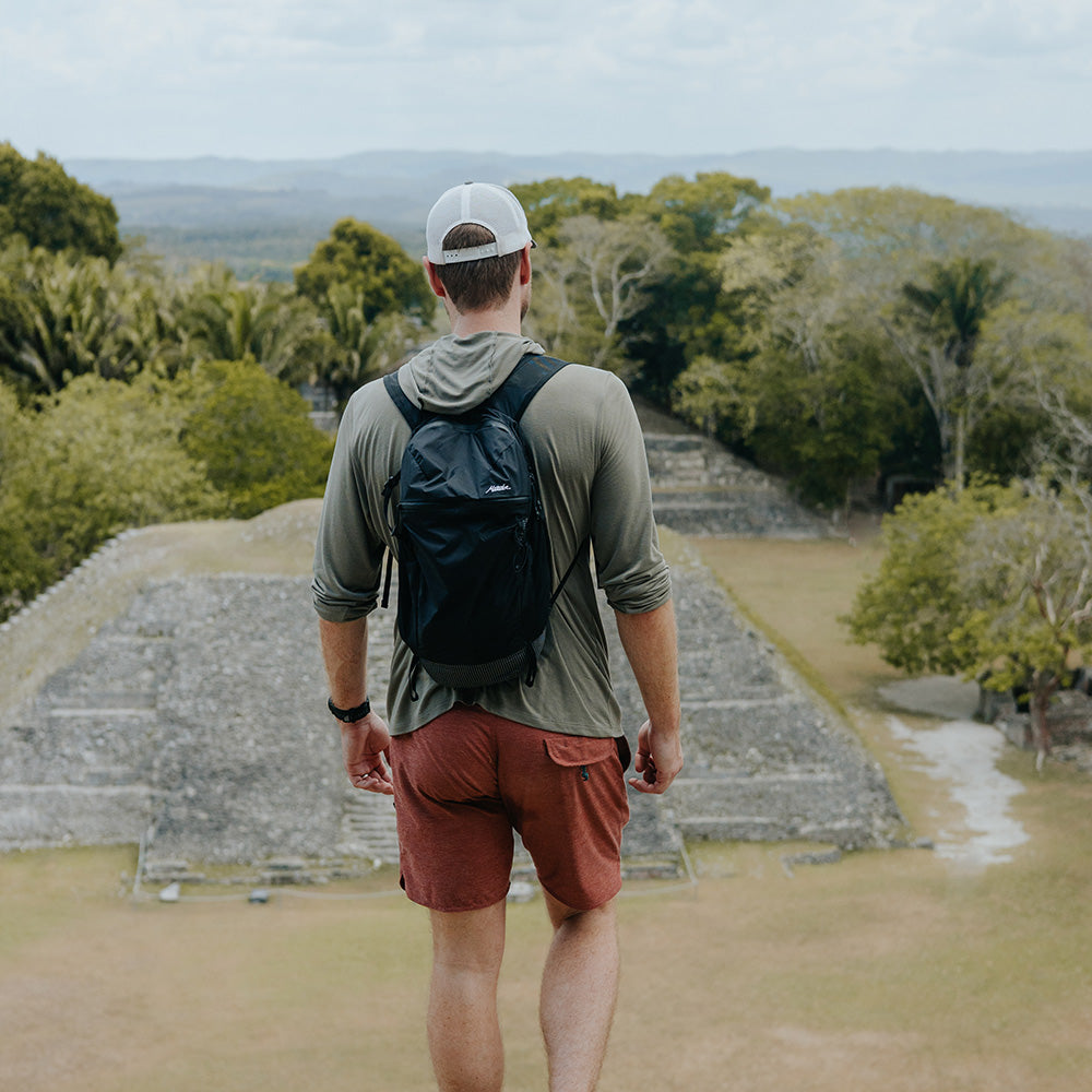 man at Belize ruins, wearing black backpack