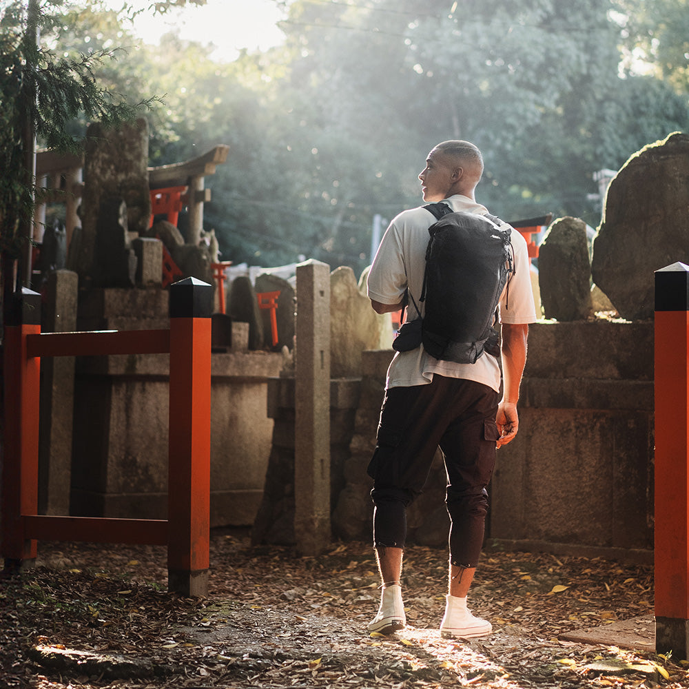 man wearing black backpack near torii gates