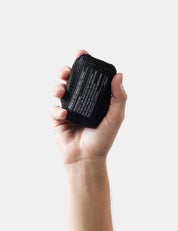 Hand holding a black textured object against a white background