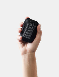 Hand holding a black textured object against a white background