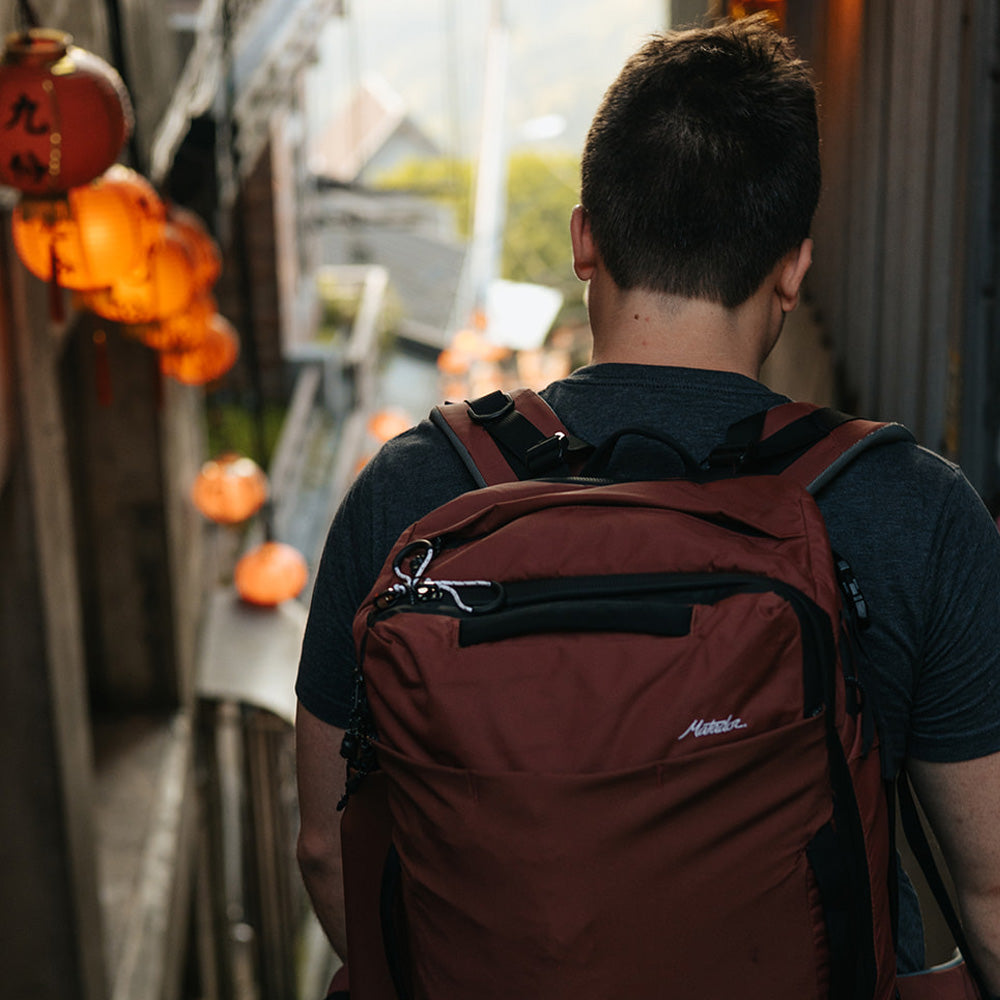 Man walking down taiwanese street wearing garnet backpack