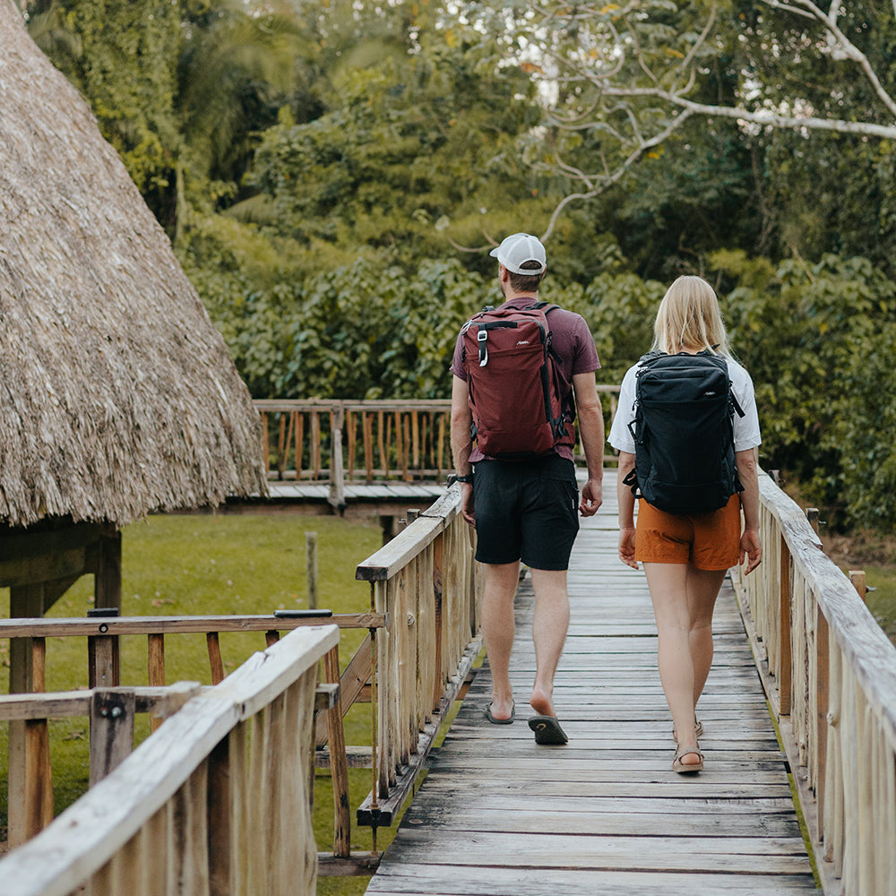 man an woman walking through Belize village wearing garnet and black globerider35 packs 