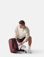 Man unpacking a red backpack on a white background