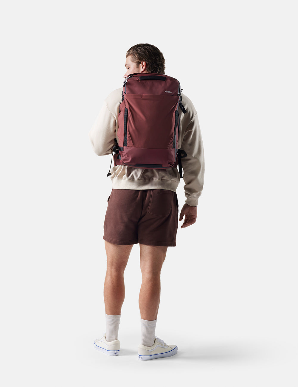 Person wearing a maroon backpack on a white background