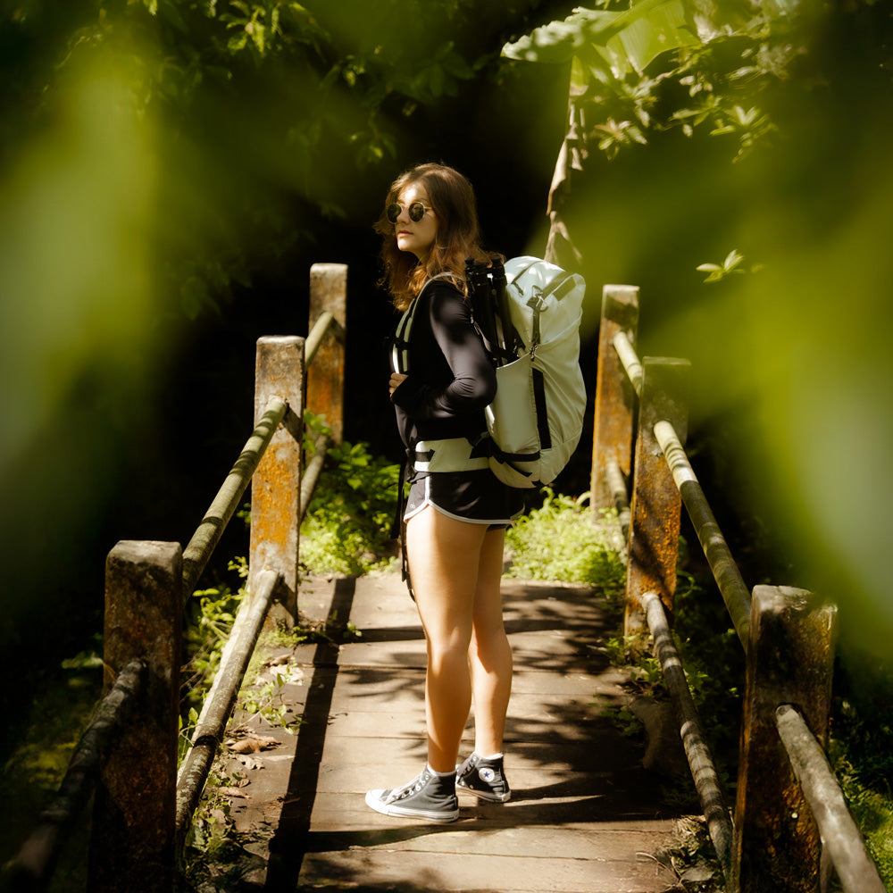 woman on tropical bridge wearing white backpack