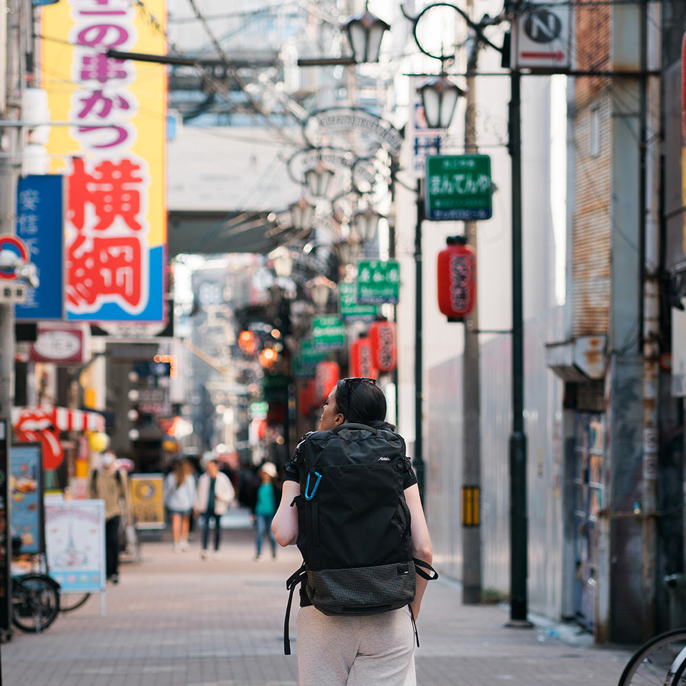 woman with black backpack walking around japan street
