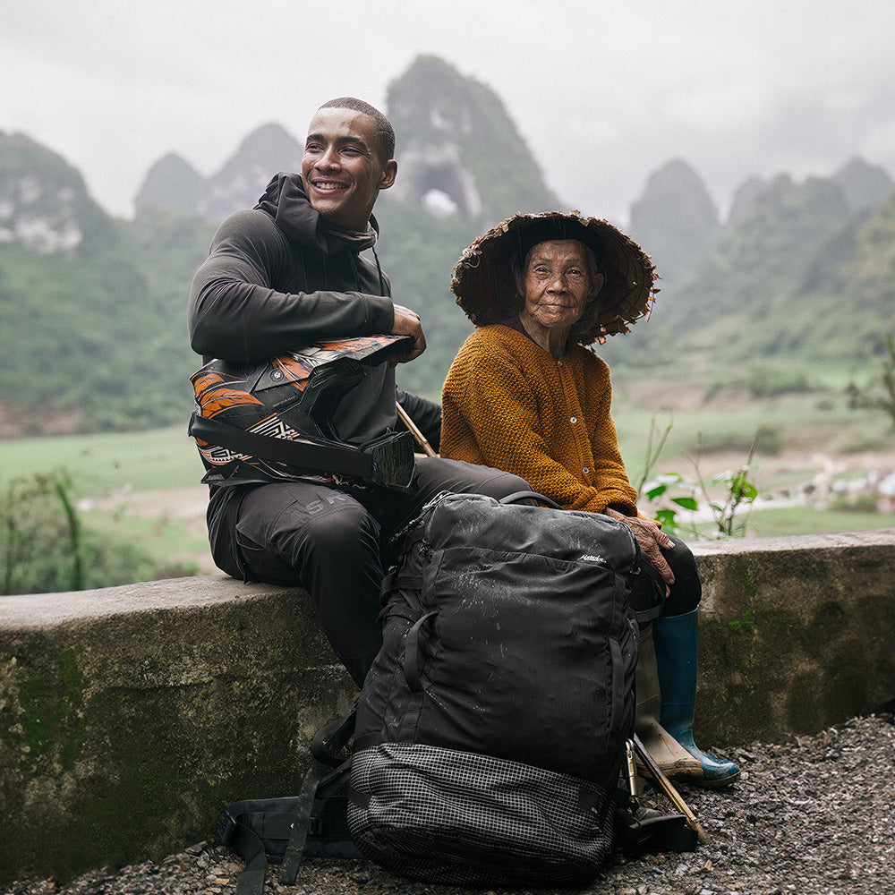 Man with black backpack sitting with local woman