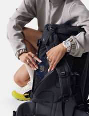 Person opening a black backpack with a white background