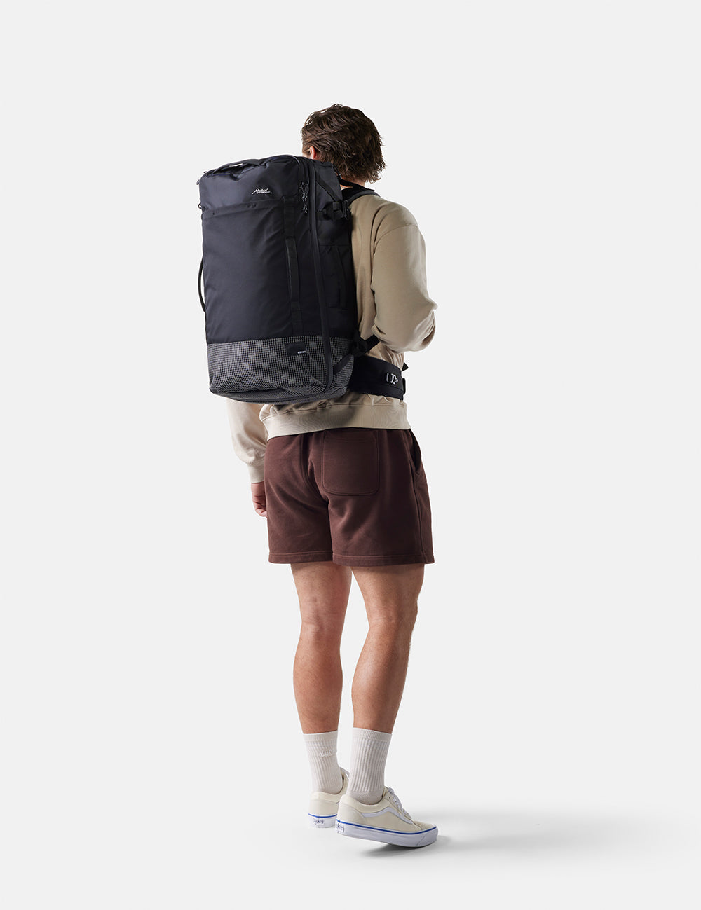 Person wearing a large black backpack on a white background