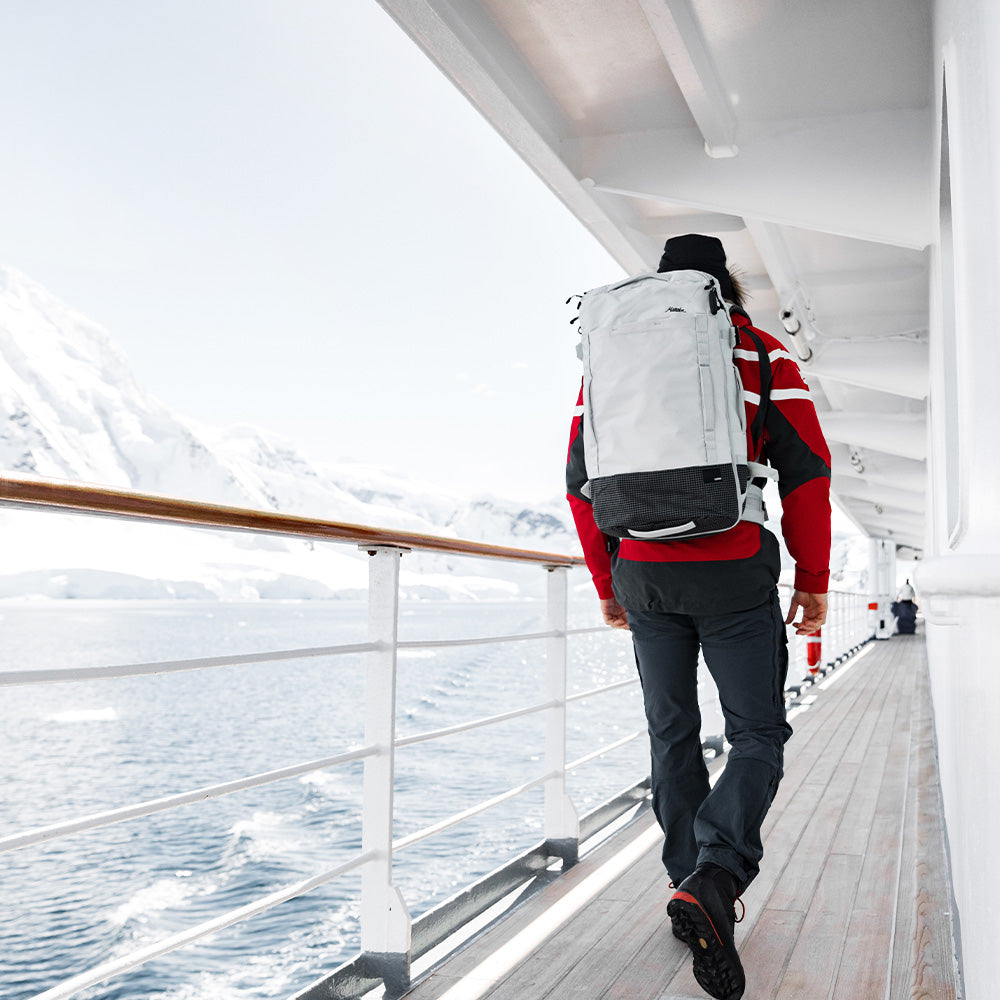 man walking along Antarctic cruise ship deck wearing white backpack