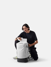 Person sitting with a large white backpack on a white background