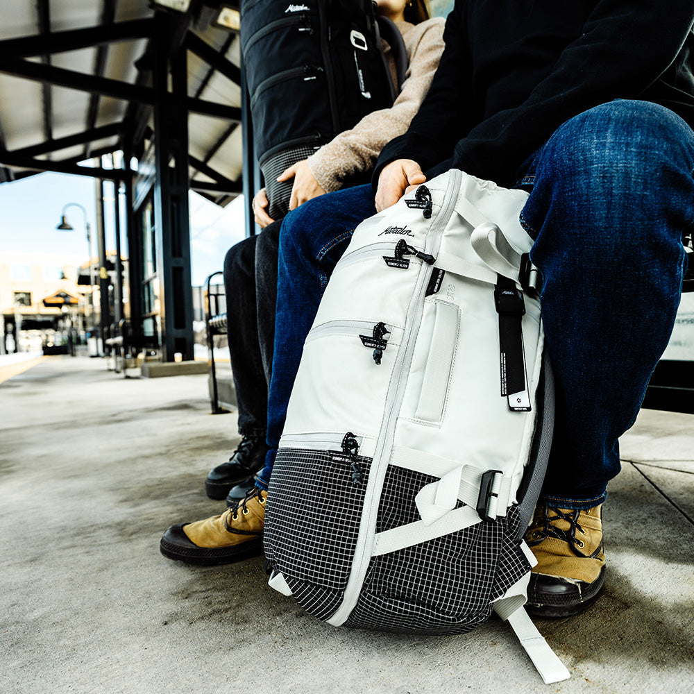 sitting at train stop with white back that has black gear tag