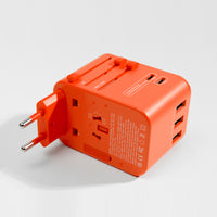 orange travel adapter laying on its side with EU prongs engaged, white background