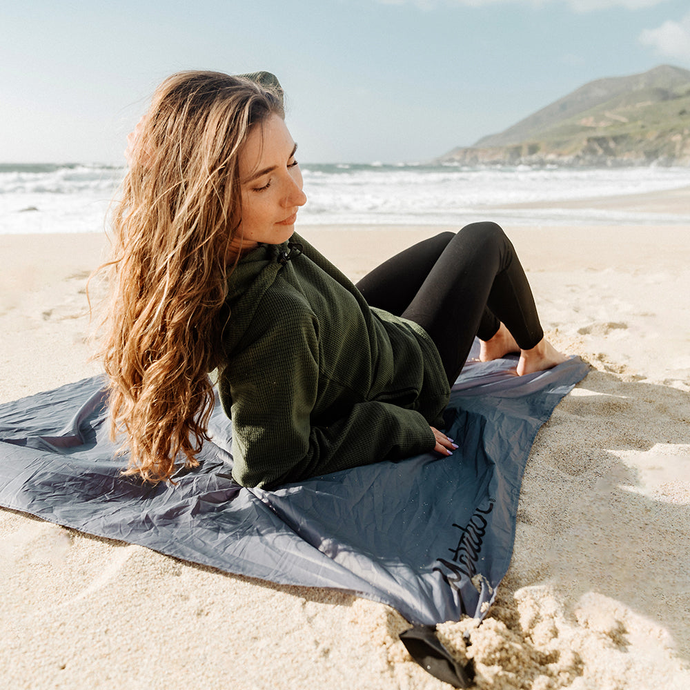 woman laying on pocket blanket on beach