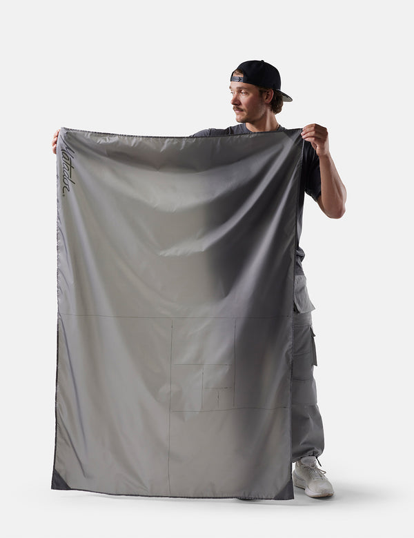 Person holding a large gray fabric against a white background