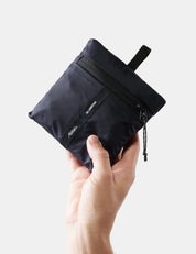 Hand holding a black pouch with a visible brand logo on a white background