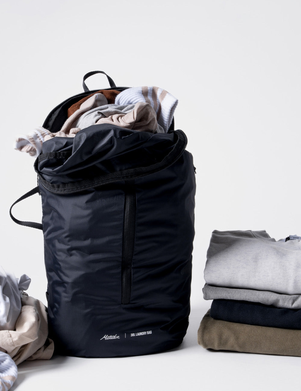 Laundry bag full of dirty laundry sitting next to folded laundry