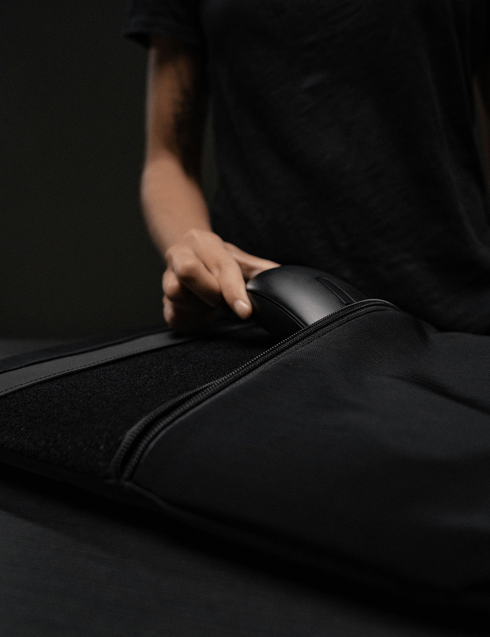 hand putting computer mouse into laptop base layer pocket