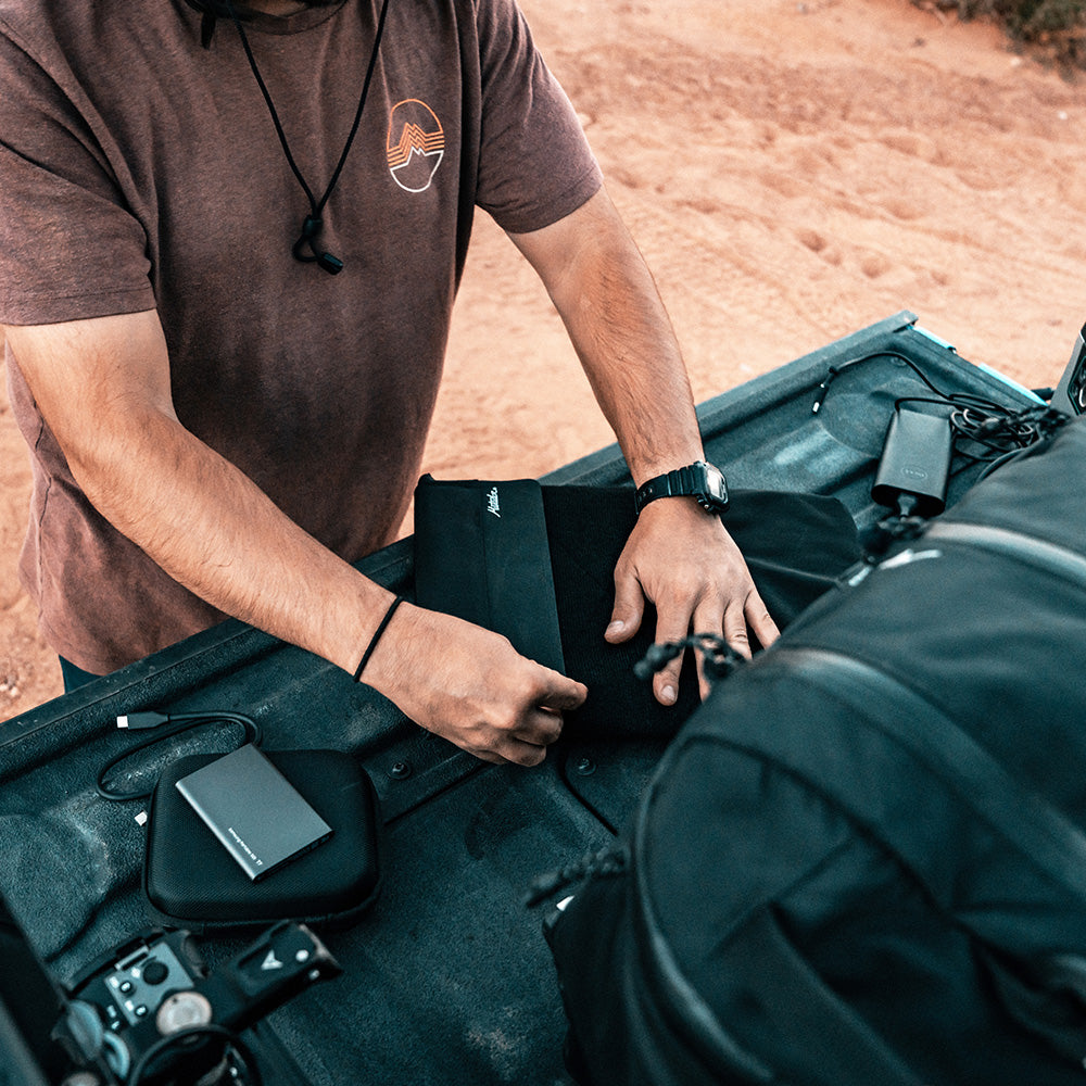 man working with electronics out of truck bed, opening laptop base layer