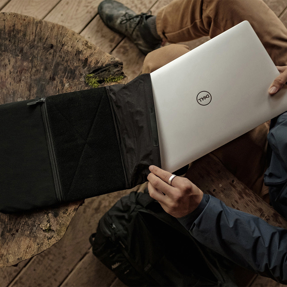 man on outdoor deck, pulling laptop out of base layer