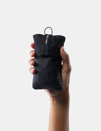 Hand holding a black compression sack with a brand logo on a white background
