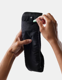 hand placing earplugs in black sleepmask on white background