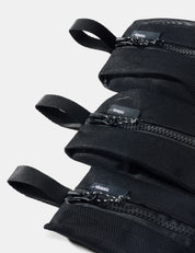 Stack of black pouches with zippers on a light gray background