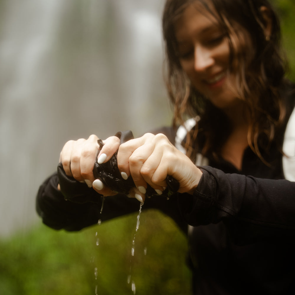 woman near waterfalls squeezing water out of towel