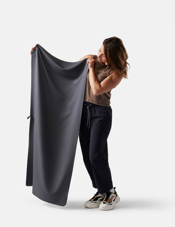 Person holding a large dark gray towel against a white background