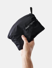 Black pouch held by a hand against a light gray background