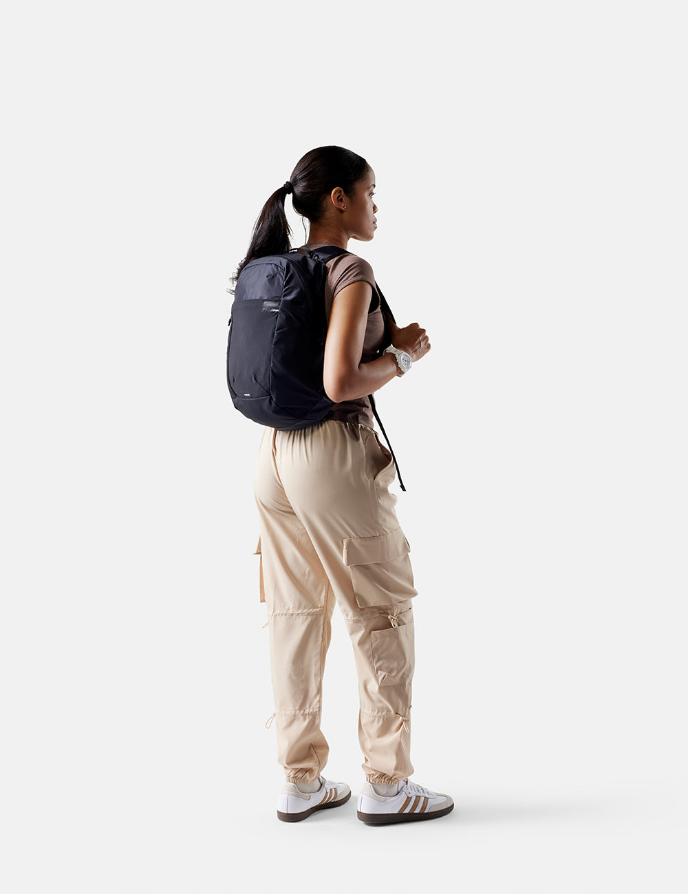 Person wearing a black backpack and beige pants on a white background