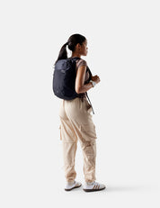 Person wearing a black backpack and beige pants on a white background