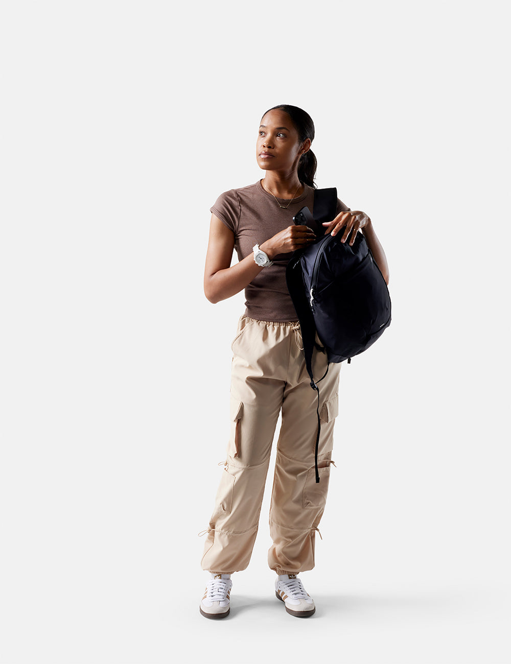 Woman holding a black backpack against a white background