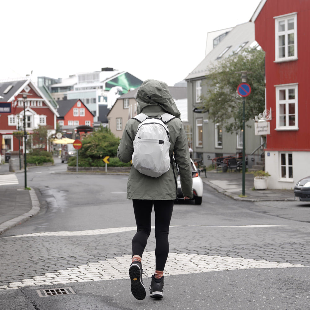 person walking in rainy European town, wearing a white backpack