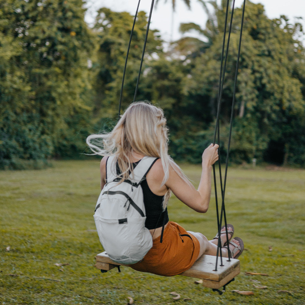woman on swing in Belize wearing white backpack