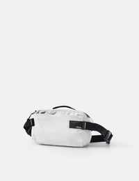 White waist bag with black strap on a light gray background