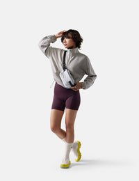Person wearing a gray jacket, purple shorts, and white sneakers on a white background