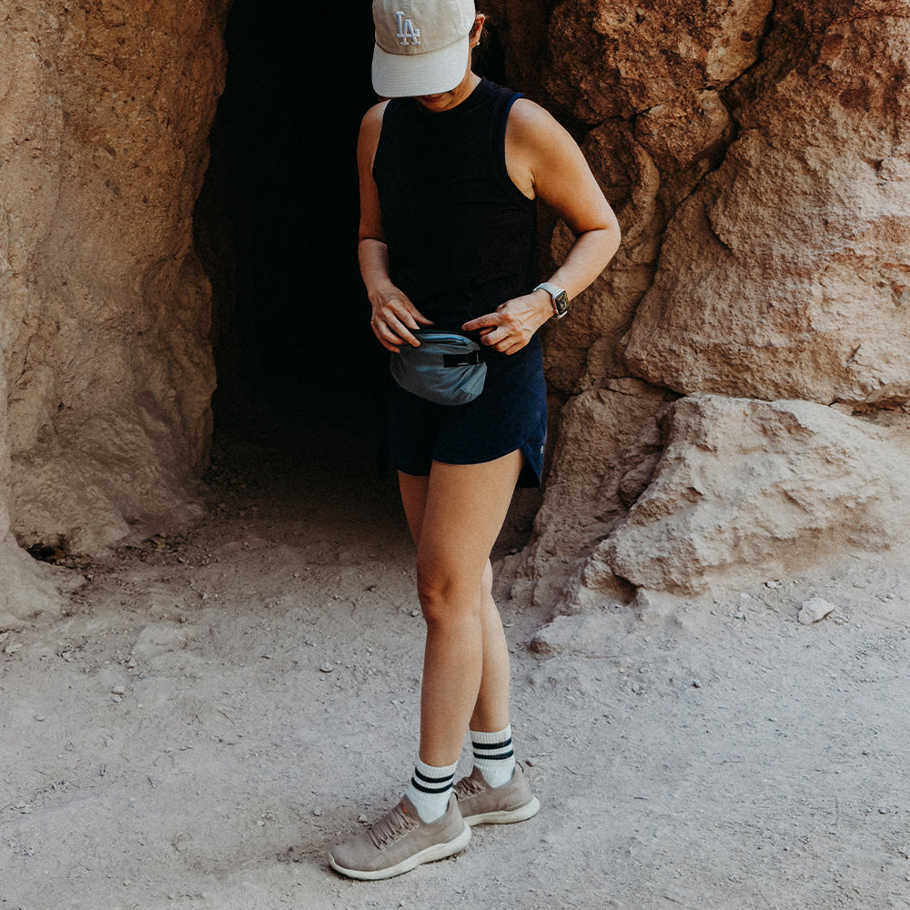 woman in front of rocky cave, wearing hip pack