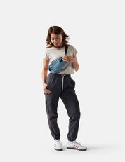 Person wearing a blue waist bag and dark pants on a white background