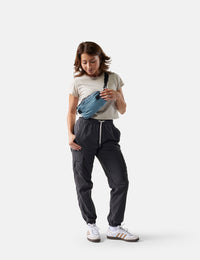 Person wearing a blue waist bag and dark pants on a white background