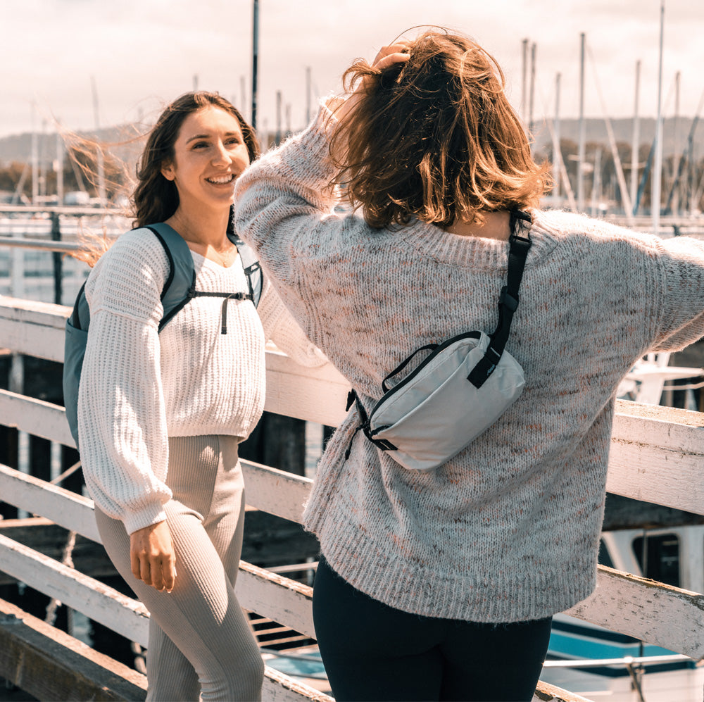 2 women chatting at sailboat docks, wearing backpack and sling
