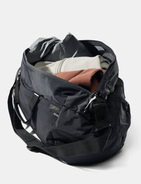 Black travel bag with clothes inside on a white background