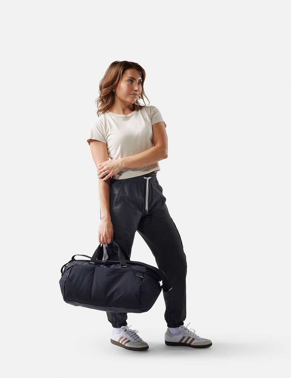 Woman holding a black duffel bag on a white background