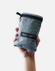 Hand holding a gray compression bag with a brand label on a white background