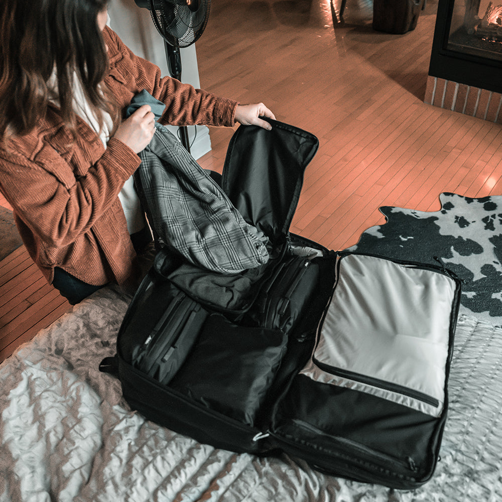 woman in cozy room, taking flannel out of black packing cube