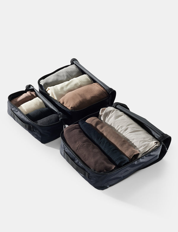 Black packing cube with folded clothes on a white background