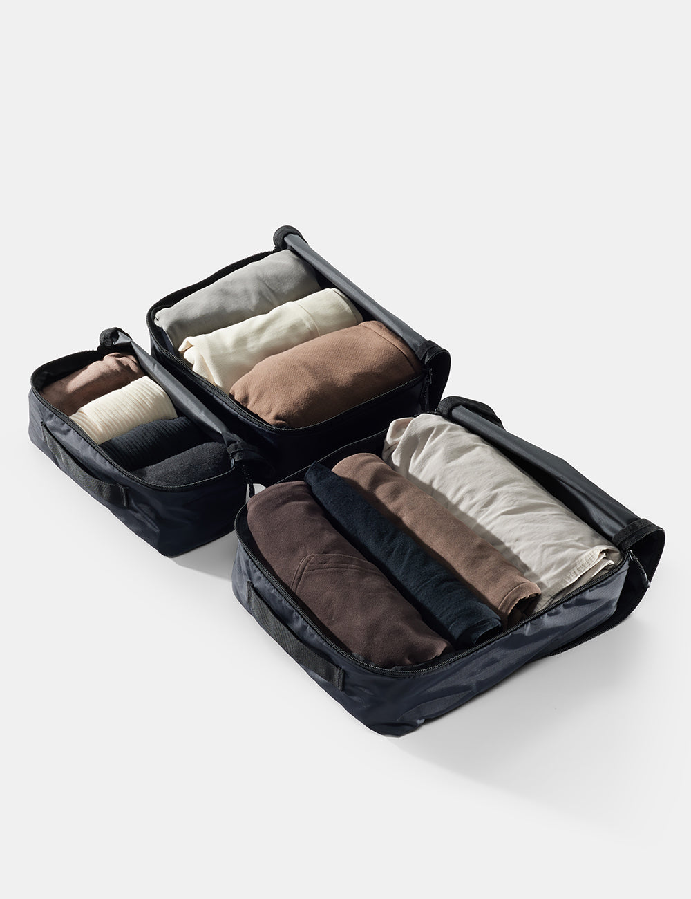 Black packing cube with folded clothes on a white background